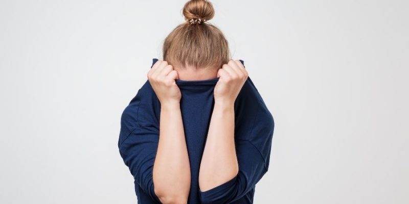 A women hiding her head in shame. The main image for "Changing Our Relationship with Failure".
