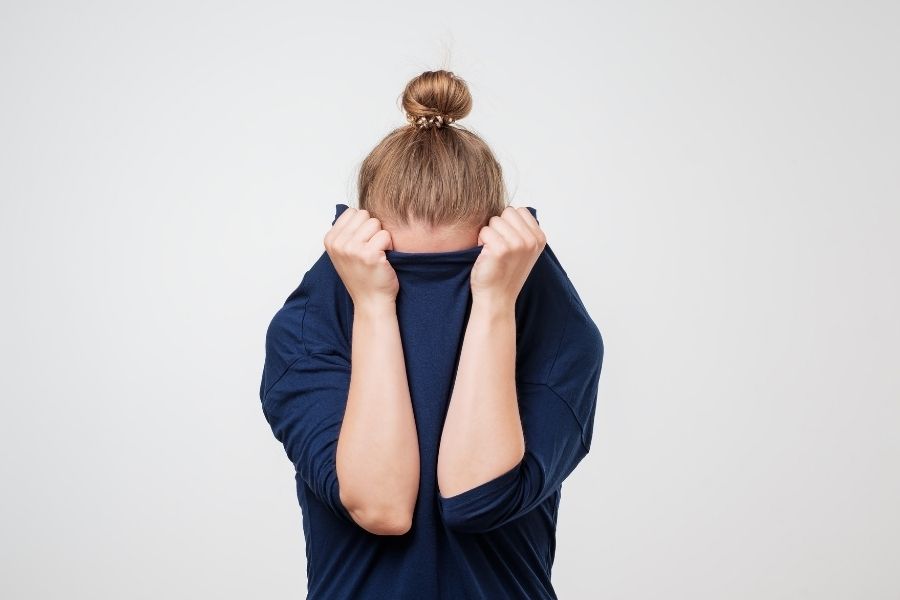 A women hiding her head in shame. The main image for "Changing Our Relationship with Failure".